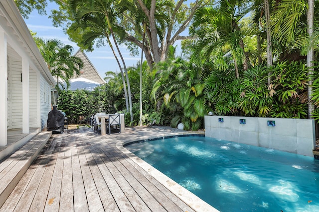 view of swimming pool featuring outdoor dining area, a wooden deck, and grilling area