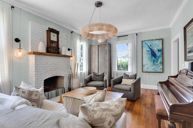 living room with hardwood / wood-style floors, crown molding, a brick fireplace, and baseboards