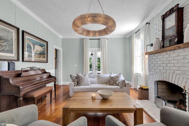 living room with ornamental molding, wood finished floors, baseboards, and a brick fireplace