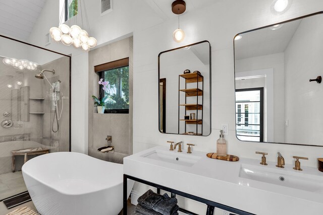 bathroom with healthy amount of natural light, walk in shower, a freestanding tub, double vanity, and vaulted ceiling