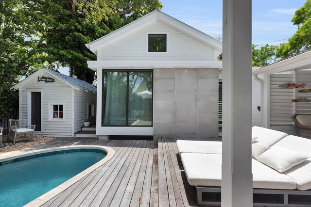 outdoor pool with a deck, an outbuilding, and an exterior structure