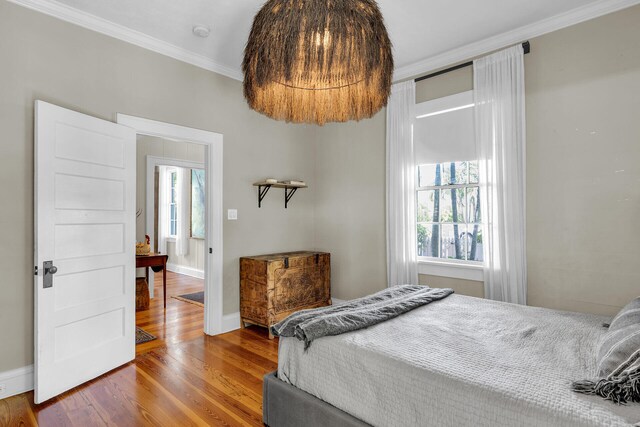 bedroom with ornamental molding, wood finished floors, and baseboards