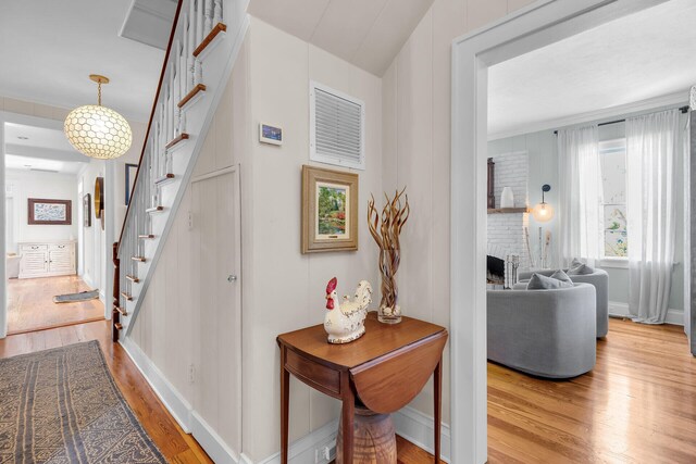 hallway with light wood-type flooring, stairway, and baseboards