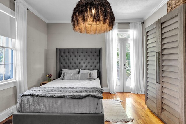 bedroom with ornamental molding, wood finished floors, french doors, and access to outside
