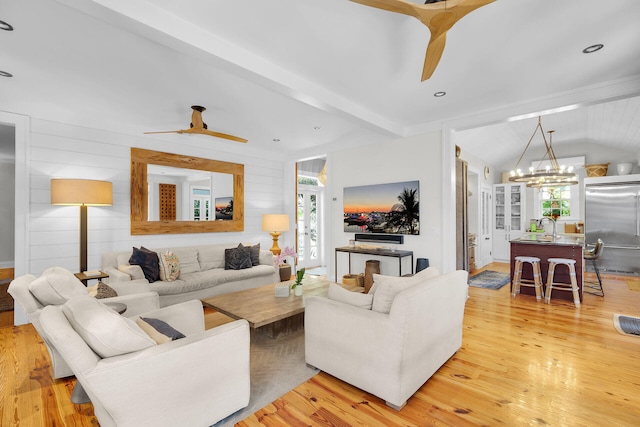 living area featuring a ceiling fan, lofted ceiling, light wood-type flooring, and a chandelier