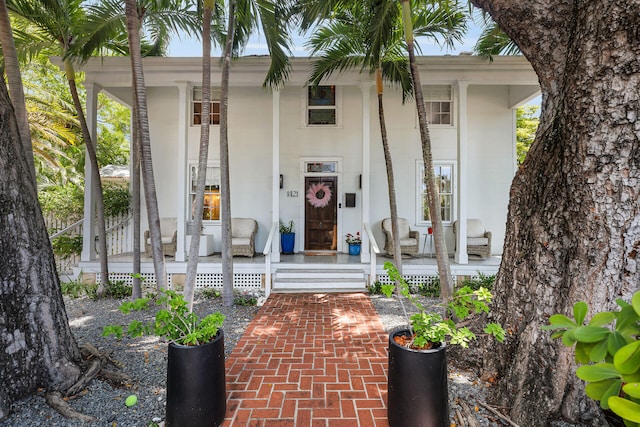 view of exterior entry featuring a porch and stucco siding
