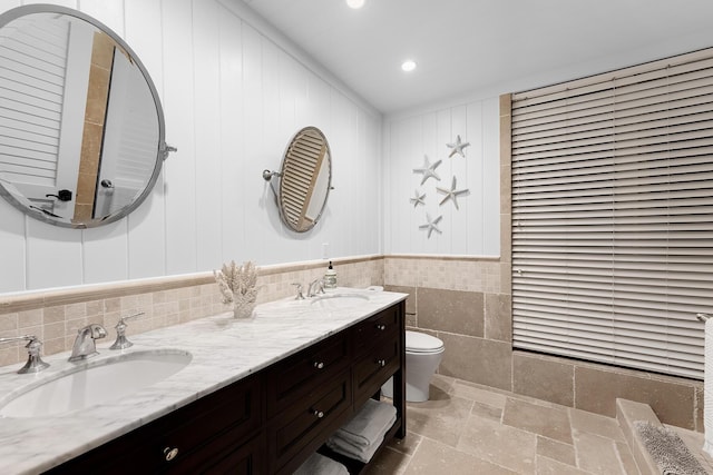 bathroom with vanity, tile walls, and toilet