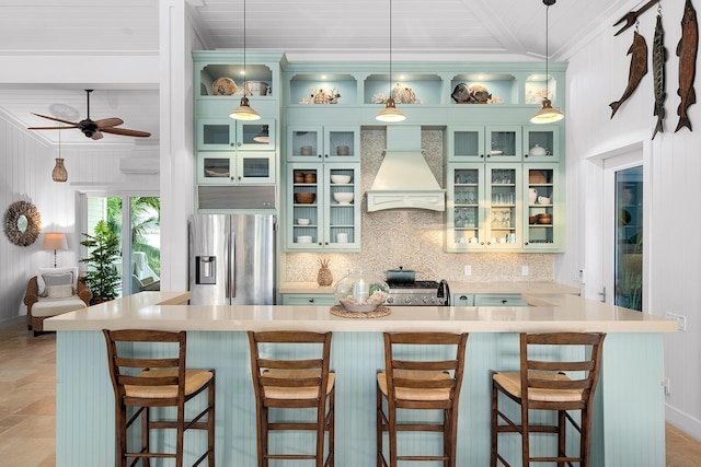 kitchen featuring stainless steel fridge with ice dispenser, a breakfast bar, hanging light fixtures, and premium range hood