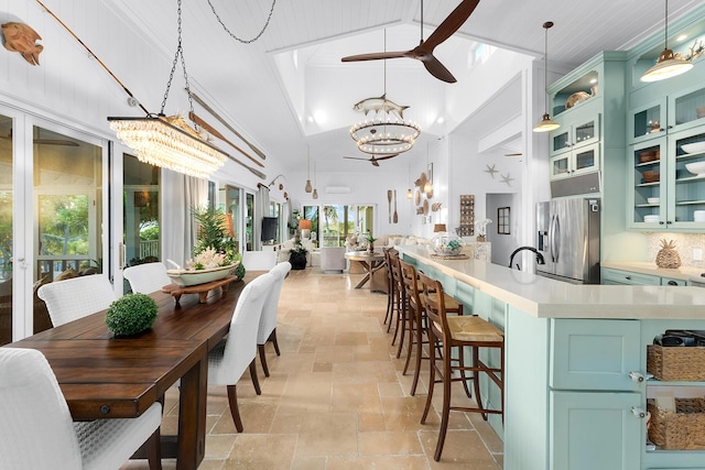 dining area featuring high vaulted ceiling and ceiling fan with notable chandelier