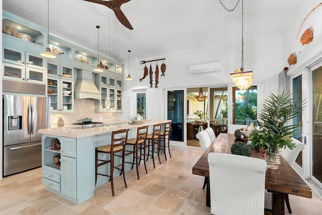 kitchen with pendant lighting, appliances with stainless steel finishes, a center island, a wall mounted AC, and custom range hood