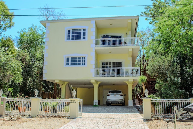 235 Buttonwood Shores Dr, Key Largo, FL 33037 - view of front of home with a carport, decorative driveway, a fenced front yard, a balcony, and stucco siding