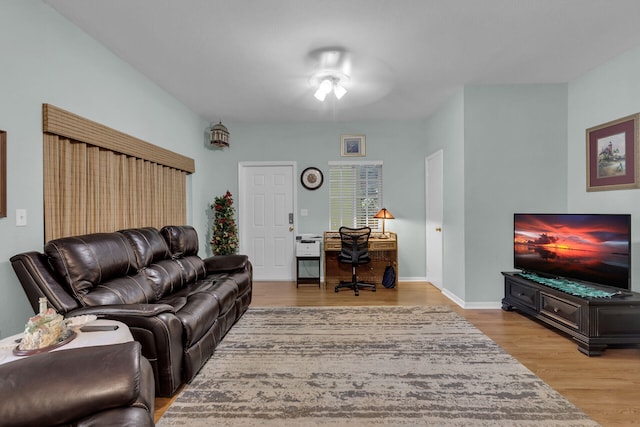 living area featuring baseboards, a ceiling fan, and wood finished floors