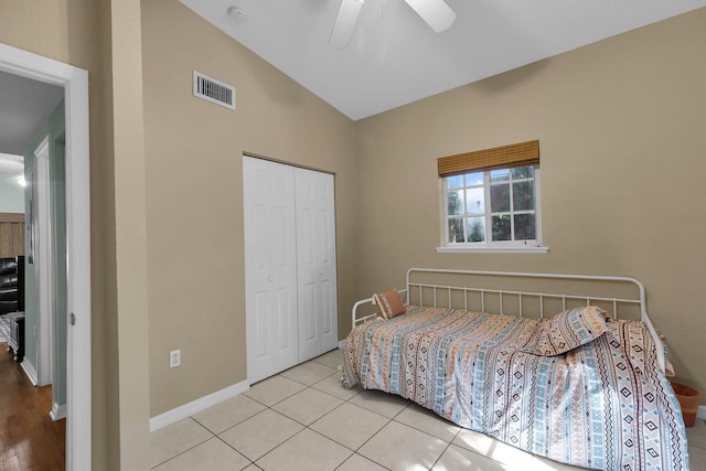 tiled bedroom with ceiling fan, vaulted ceiling, and a closet