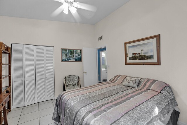 tiled bedroom with ceiling fan, vaulted ceiling, and a closet