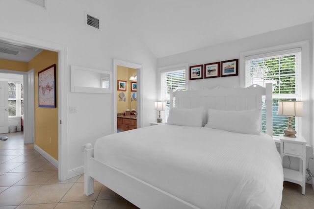 bedroom featuring light tile patterned floors, ensuite bath, and vaulted ceiling