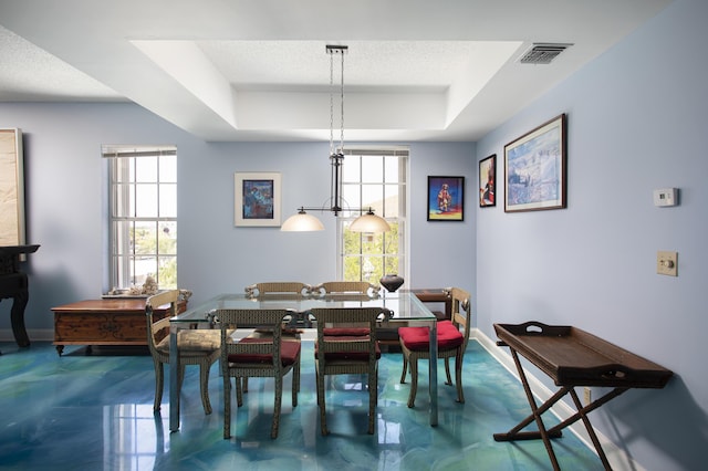 dining room featuring plenty of natural light, a tray ceiling, concrete flooring, and a textured ceiling