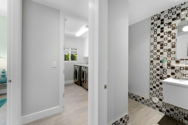 bathroom with baseboards, wood finished floors, and washing machine and clothes dryer