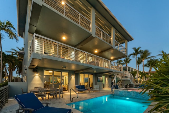 rear view of house featuring an outdoor living space, stucco siding, a patio, a balcony, and stairs