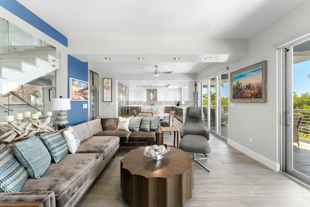 living area with a healthy amount of sunlight, light wood-style floors, a ceiling fan, and baseboards