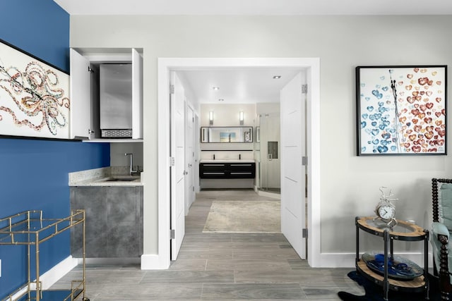 hall featuring a sink, wood finished floors, and baseboards