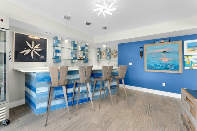 bar featuring a chandelier, wood finished floors, and baseboards