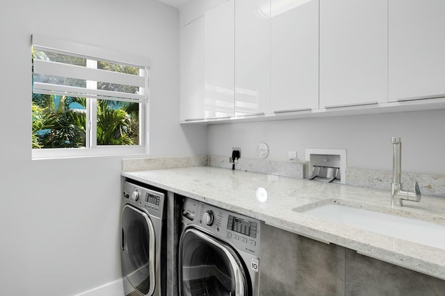 laundry area with washing machine and dryer, cabinet space, and a sink