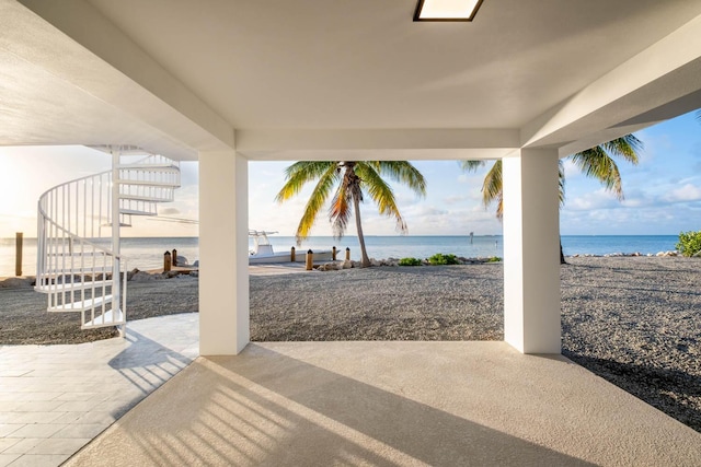 view of patio featuring a water view, a beach view, and stairs