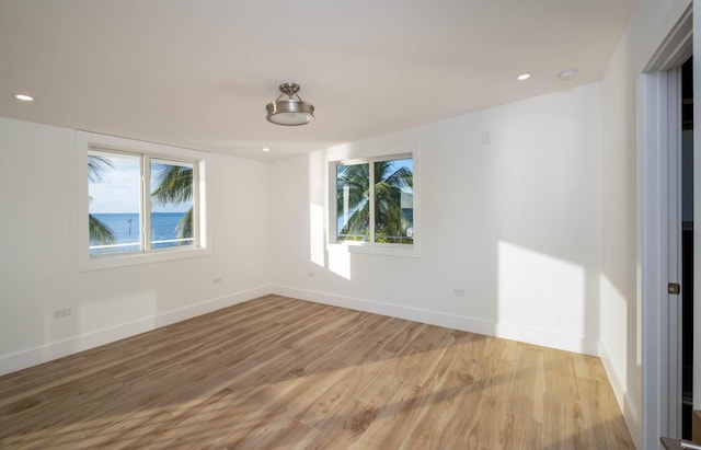 empty room featuring light wood finished floors, recessed lighting, and baseboards