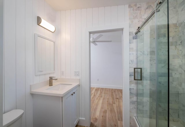 full bathroom with toilet, a stall shower, ceiling fan, vanity, and wood finished floors