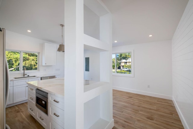 kitchen with stainless steel appliances, a sink, white cabinets, and light stone countertops