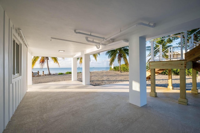 view of patio with stairs, a beach view, and a water view