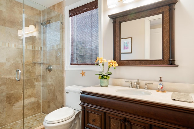 bathroom featuring vanity, toilet, and a shower with shower door