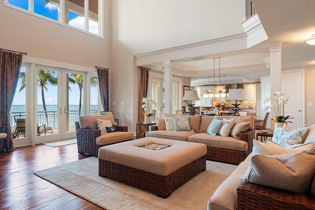 living room featuring a water view, decorative columns, french doors, and light wood-type flooring