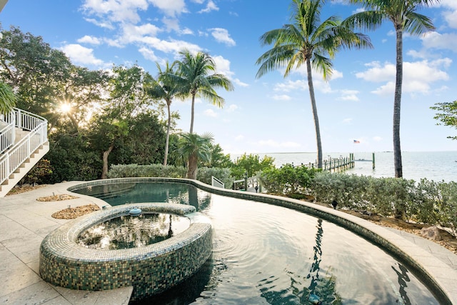 view of pool with an in ground hot tub and a water view