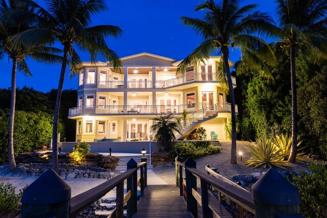 back house at night with french doors, a balcony, and a patio area