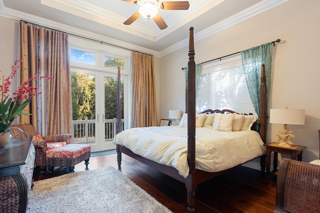 bedroom featuring dark wood-type flooring, french doors, ornamental molding, a tray ceiling, and access to exterior