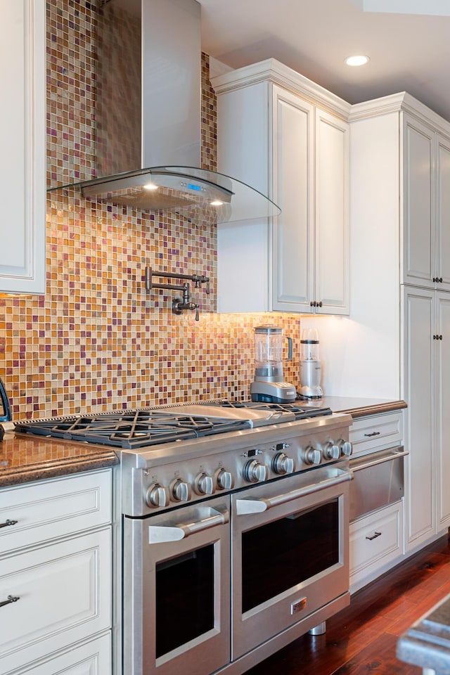 kitchen featuring wall chimney exhaust hood, white cabinetry, double oven range, dark hardwood / wood-style floors, and backsplash