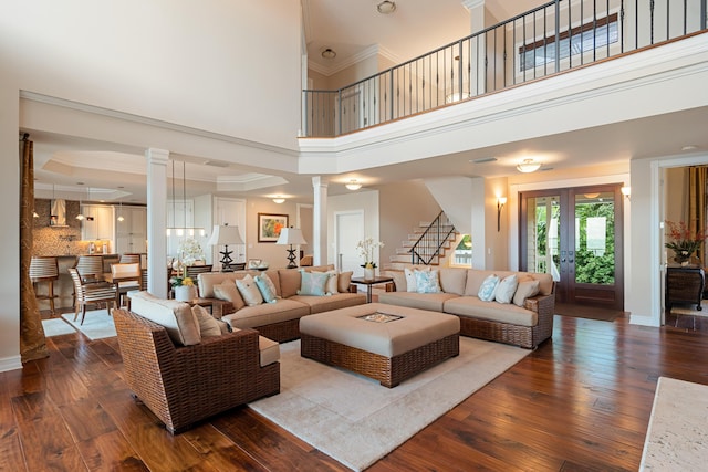 living room with wood-type flooring, decorative columns, and french doors