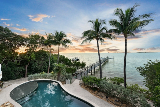 pool at dusk with a water view and a boat dock