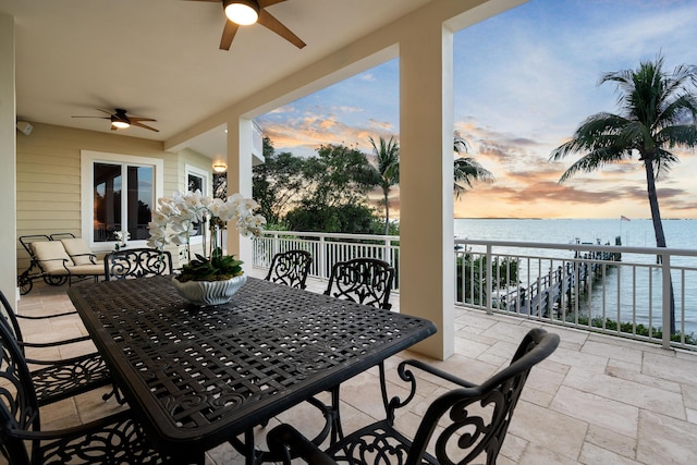 patio terrace at dusk with a water view and ceiling fan