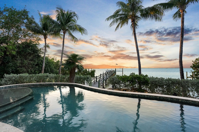 pool at dusk featuring a water view