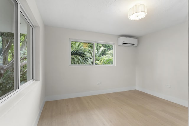 unfurnished room featuring an AC wall unit and light wood-type flooring