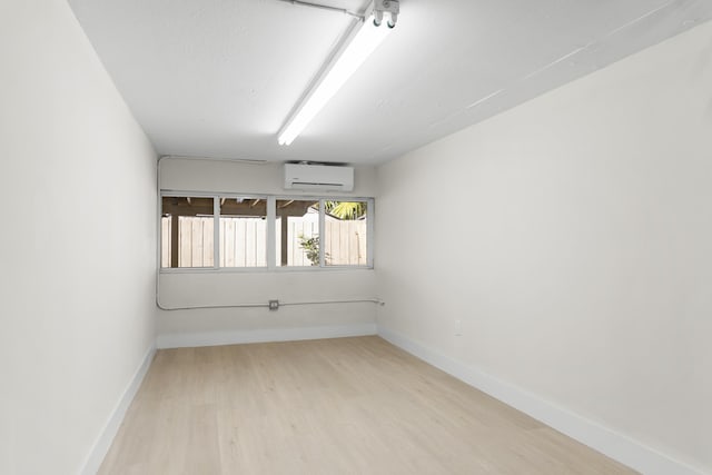 empty room with a wall mounted air conditioner and light hardwood / wood-style floors