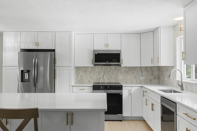 kitchen with stainless steel appliances, sink, white cabinets, and decorative backsplash