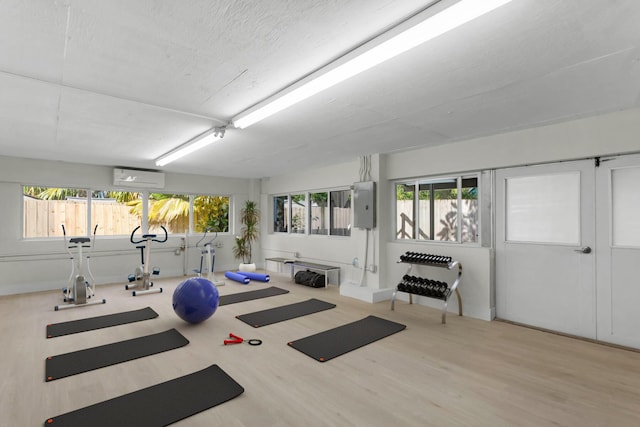 exercise area with a wall mounted air conditioner and light hardwood / wood-style floors