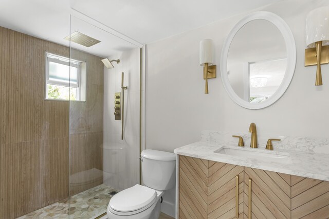 bathroom with a tile shower, vanity, and toilet