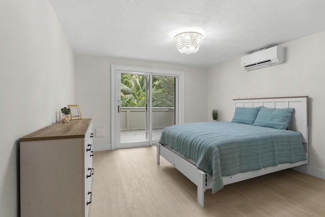 bedroom featuring a wall mounted air conditioner, light wood-type flooring, and access to outside