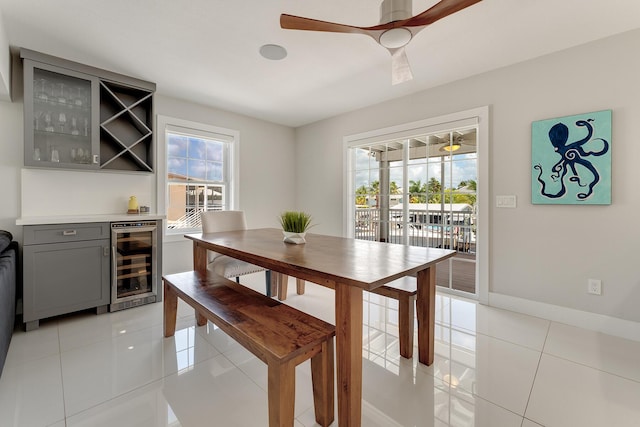 dining space with wine cooler, light tile patterned floors, ceiling fan, and bar area