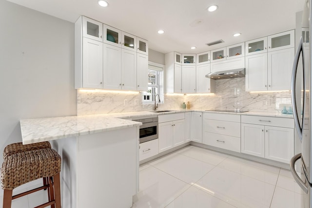 kitchen with white cabinetry, sink, a kitchen breakfast bar, kitchen peninsula, and light stone countertops