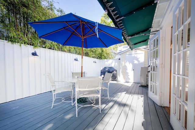 wooden deck with fence, grilling area, and outdoor dining space